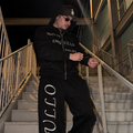 Model wearing black M&N Orgullo rhinestone zip-up hoodie on stairs