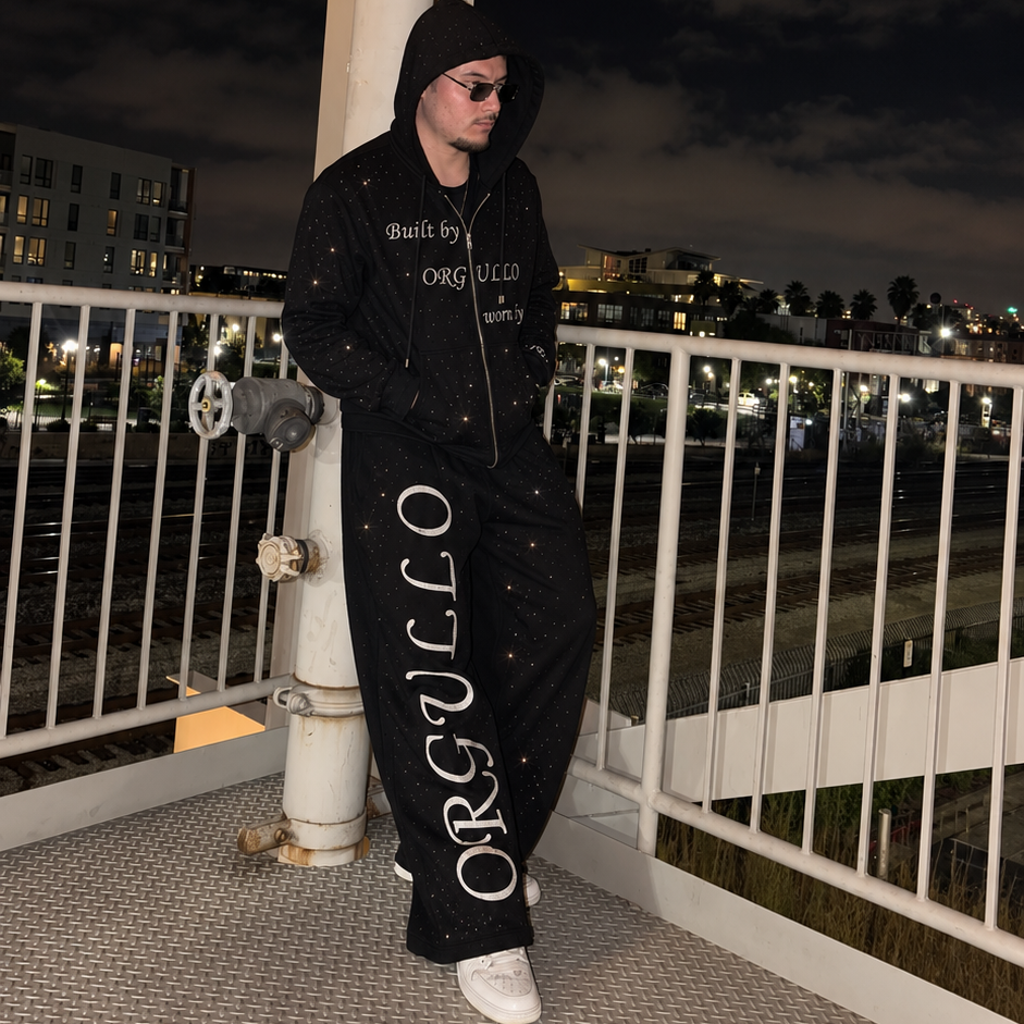Model wearing black M&N Orgullo rhinestone sweatpants at night