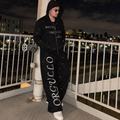 Model wearing black M&N Orgullo rhinestone sweatpants at night