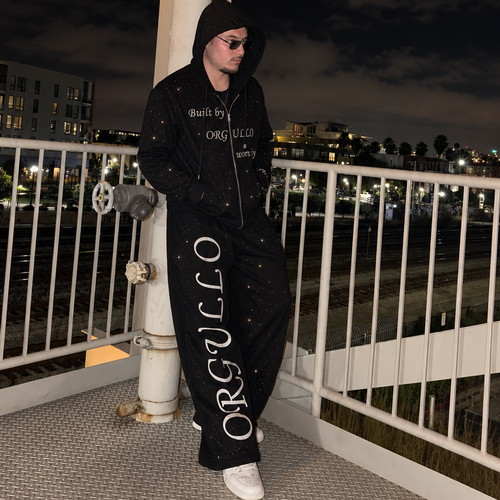 Model wearing black M&N Orgullo rhinestone sweatpants at night