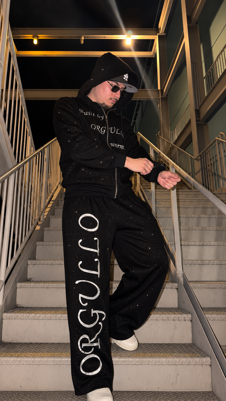 Model styling black M&N Orgullo rhinestone sweatpants on stairs