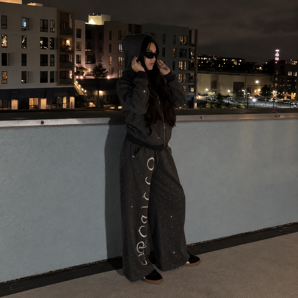 Model wearing M&N Orgullo dark gray rhinestone hoodie on rooftop at night