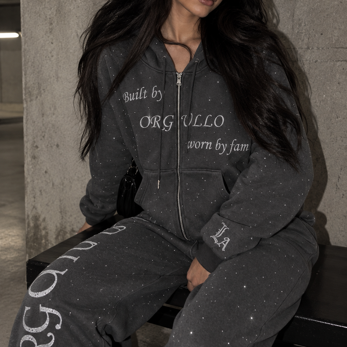 Close-up of model wearing M&N Orgullo dark gray rhinestone sweatpants and matching hoodie