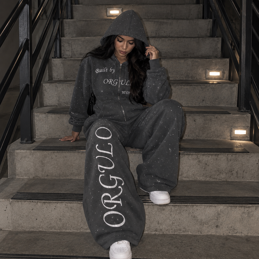 Model wearing dark gray ORGULLO rhinestone wide-leg sweatpants on stairs