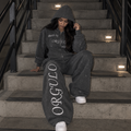 Model wearing dark gray ORGULLO rhinestone wide-leg sweatpants on stairs