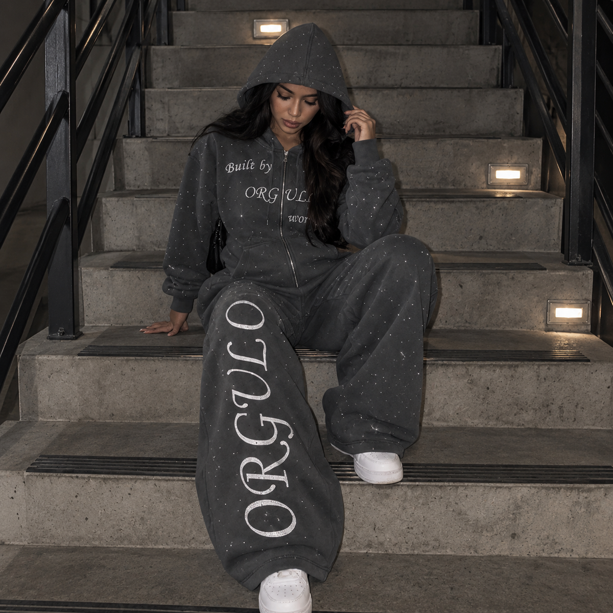 Model wearing dark gray ORGULLO rhinestone wide-leg sweatpants on stairs